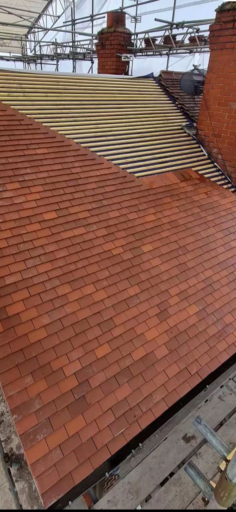 New battens and fresh clay tiles being laid on a Manchester roof